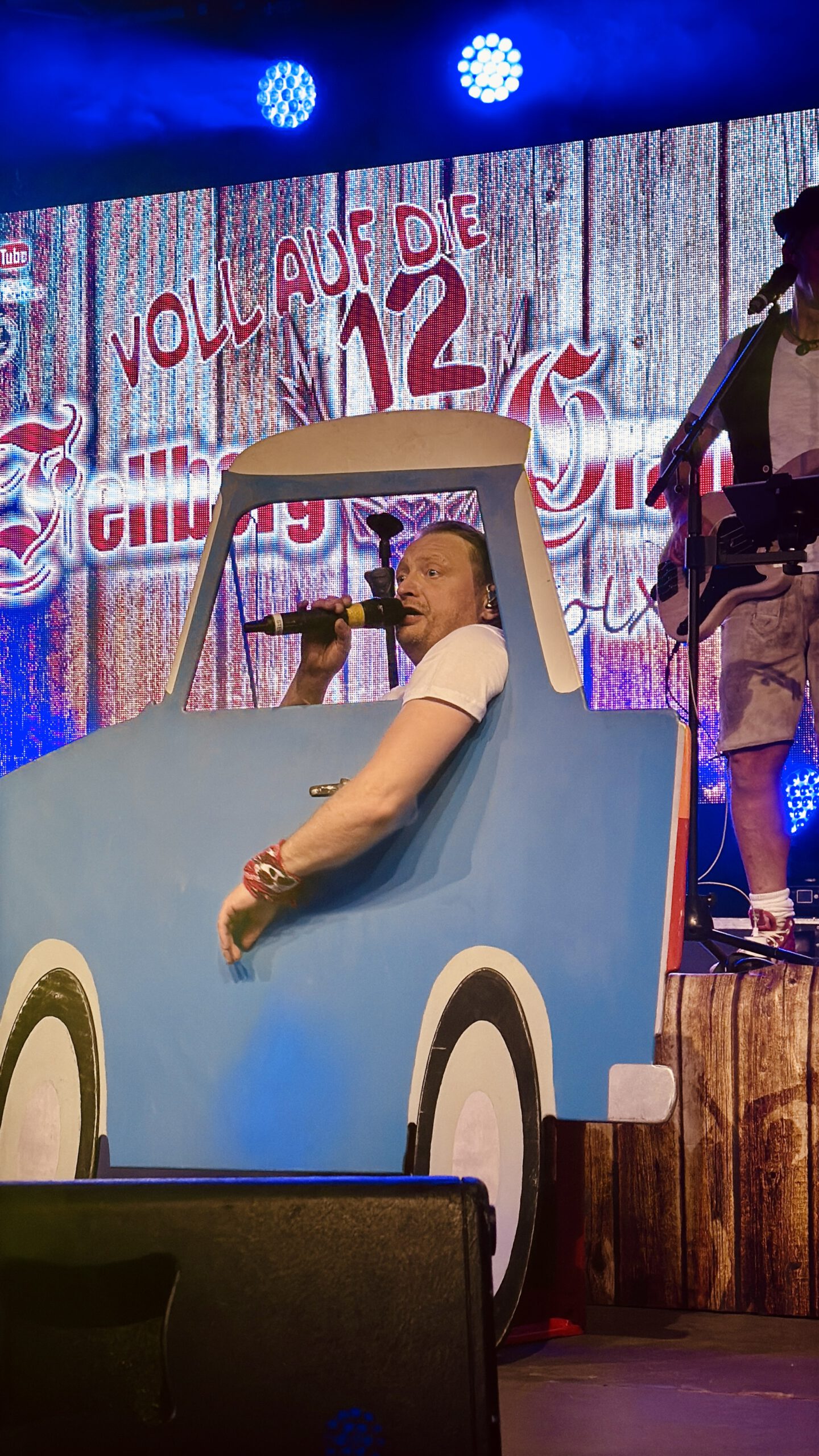 Entertainer singt auf der Bühne der Quedlinburger Wiesn im blauen Pappauto – Oktoberfest Quedlinburg